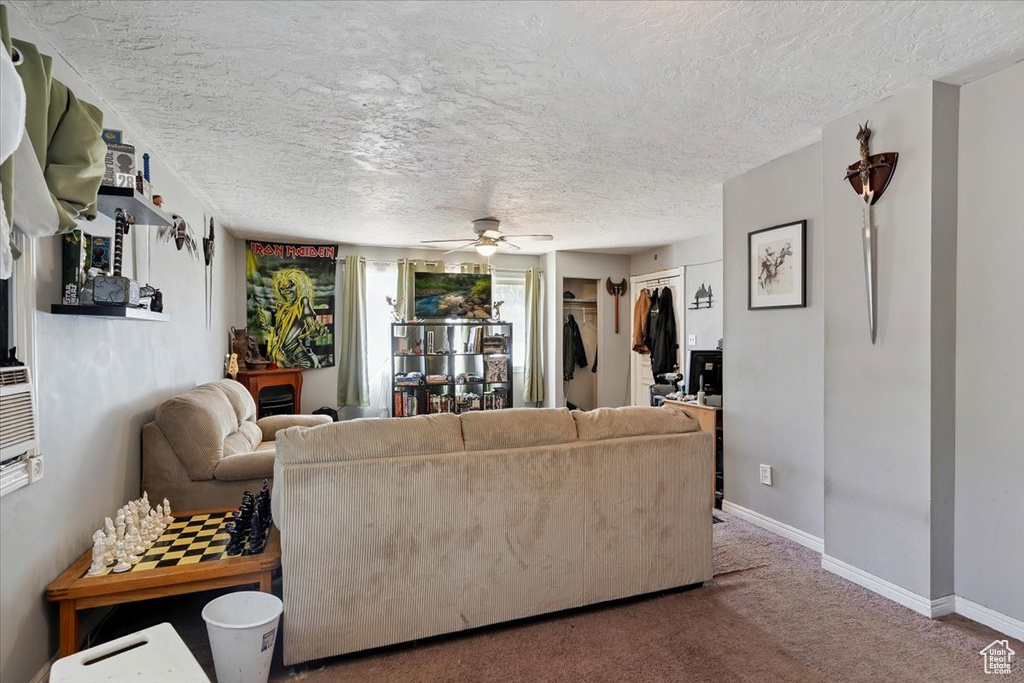 Carpeted living room with ceiling fan and a textured ceiling