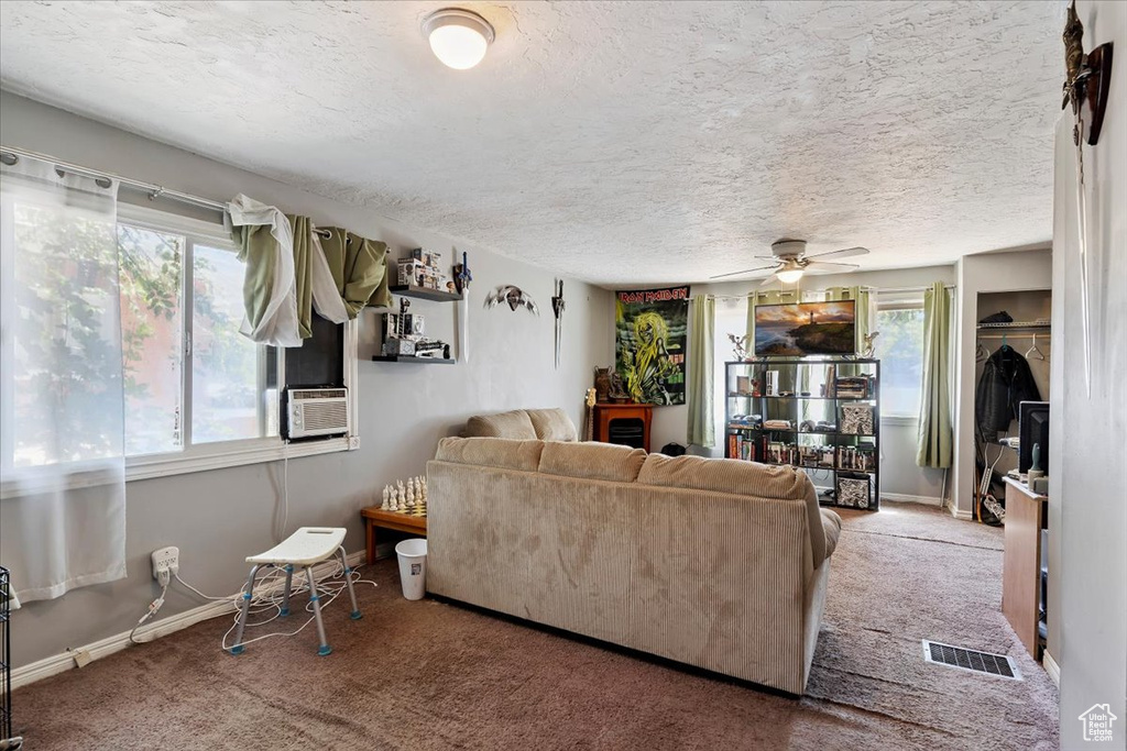 Living room with carpet floors, a ceiling fan, a textured ceiling, and cooling unit