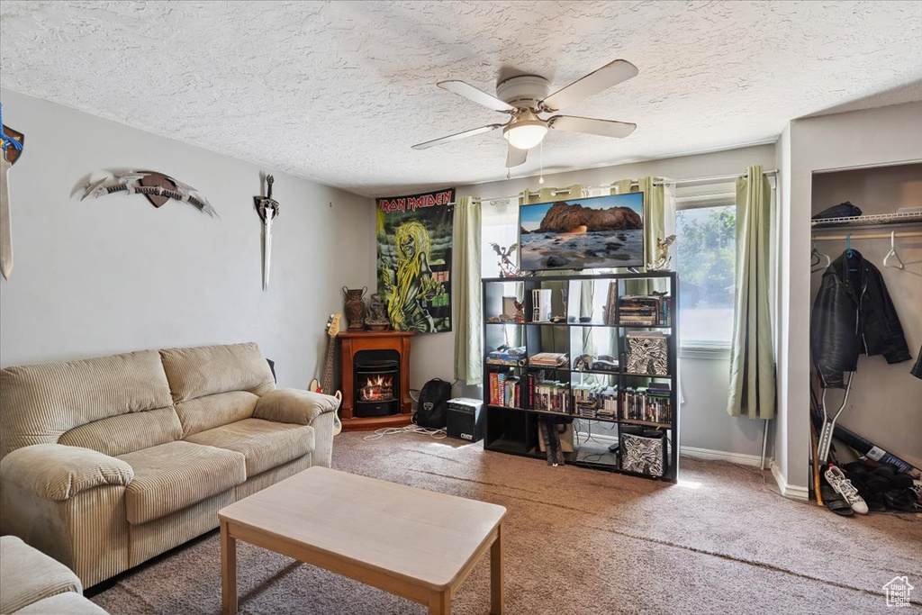 Living area featuring a ceiling fan, carpet flooring, and a textured ceiling