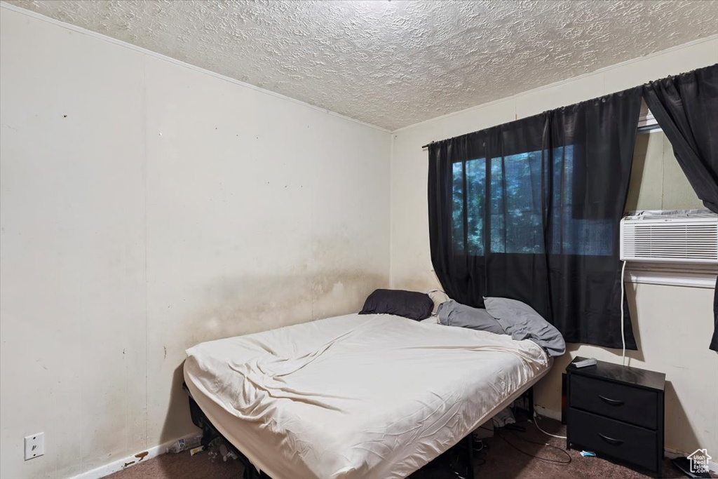 Carpeted bedroom featuring a textured ceiling and cooling unit