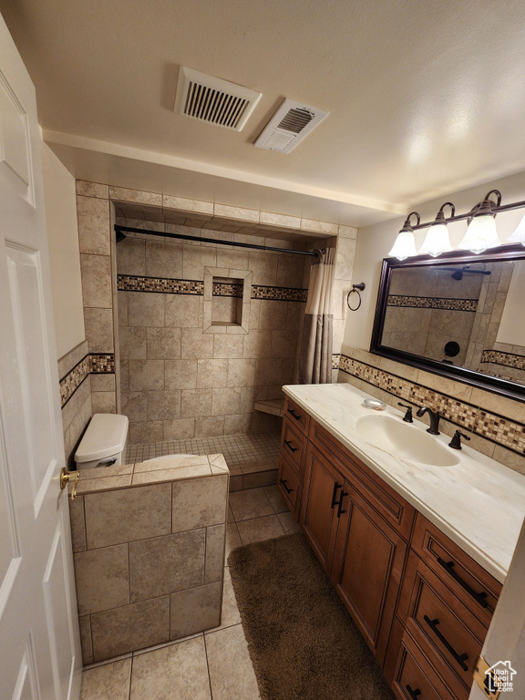 Bathroom with tile patterned floors, a tile shower, vanity, and tasteful backsplash