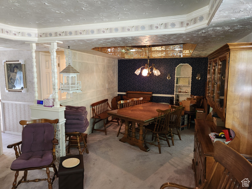 Carpeted dining room with wallpapered walls, a chandelier, and ornamental molding