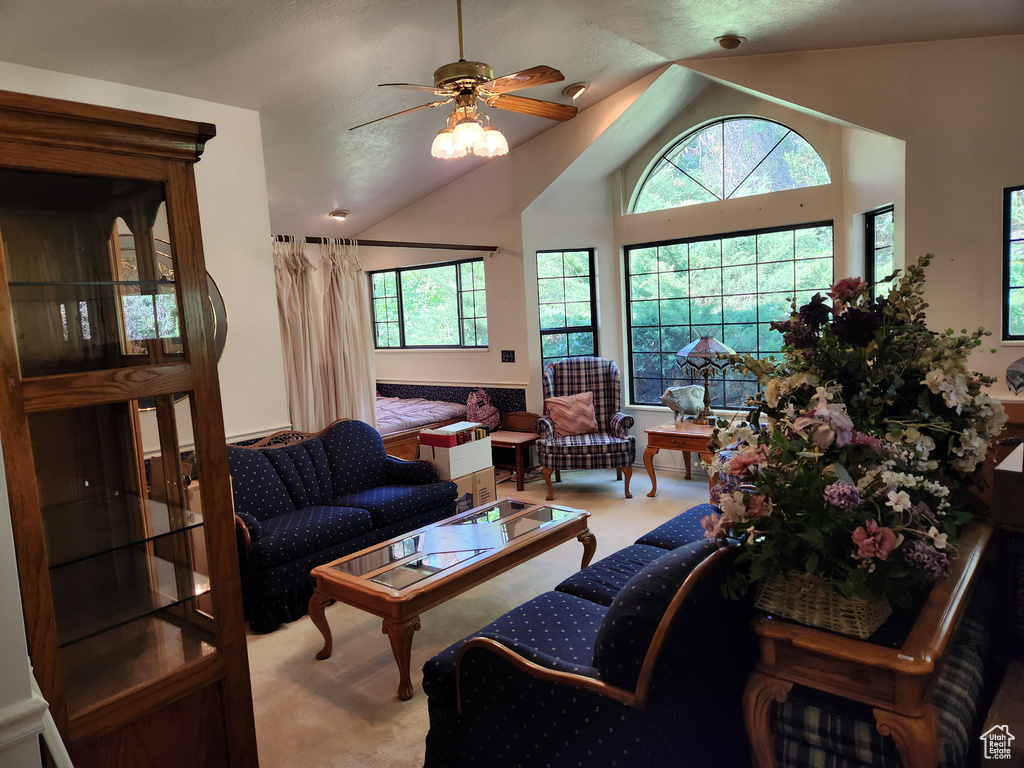 Living room with vaulted ceiling, a ceiling fan, and carpet floors