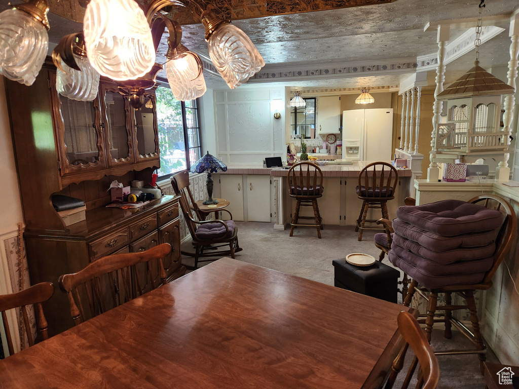 Dining space with light carpet and a chandelier