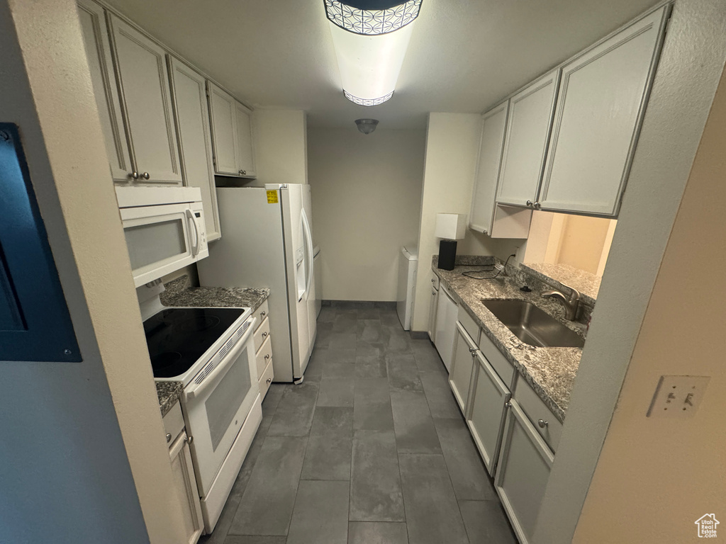Kitchen featuring white appliances, white cabinets, and stone counters