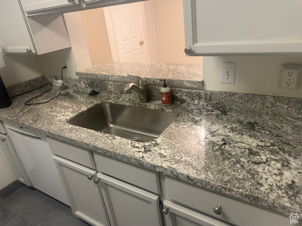 Kitchen featuring dishwasher, dark stone counters, and dark tile patterned flooring