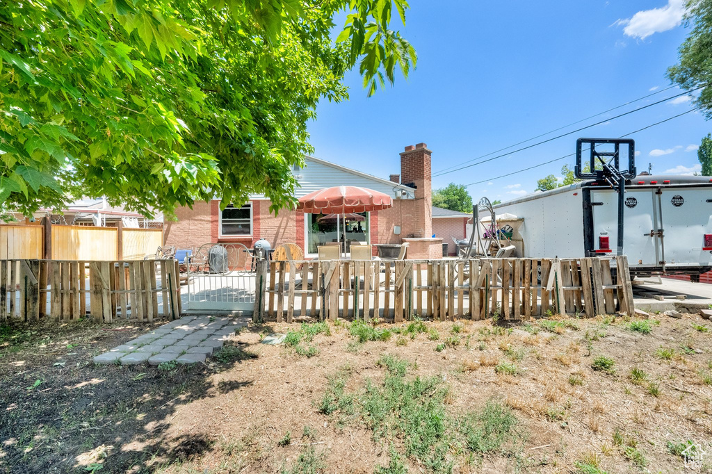 Back of property featuring a gate, a chimney, and brick siding