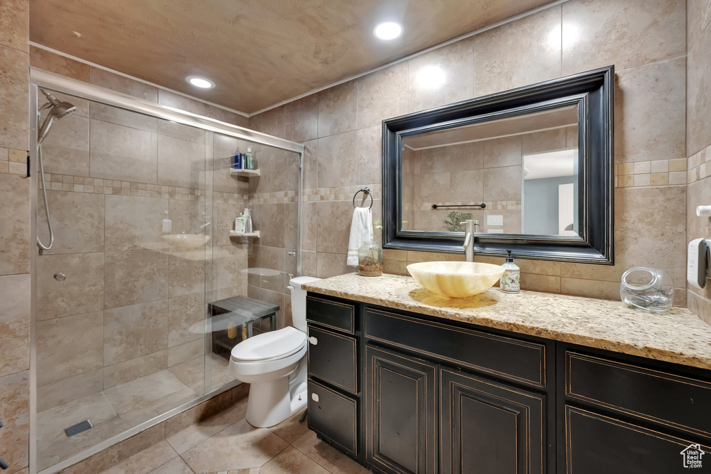 Full bathroom with tile walls, a shower stall, vanity, and tile patterned floors