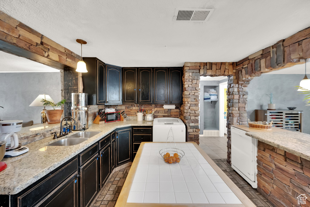 Kitchen featuring washer / clothes dryer, light countertops, hanging light fixtures, and tasteful backsplash
