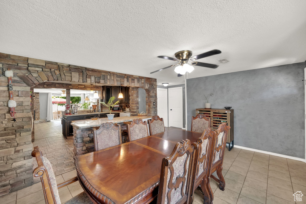 Dining area featuring a textured ceiling, ceiling fan, and light tile patterned floors