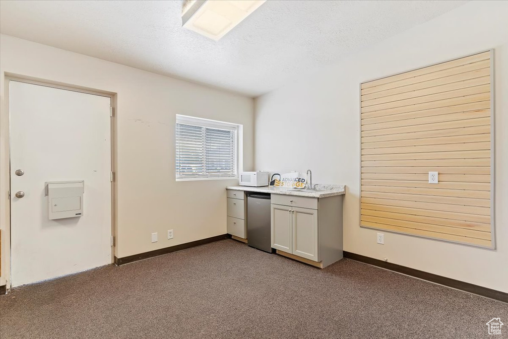 Kitchen with carpet flooring, light countertops, refrigerator, a textured ceiling, and dishwasher