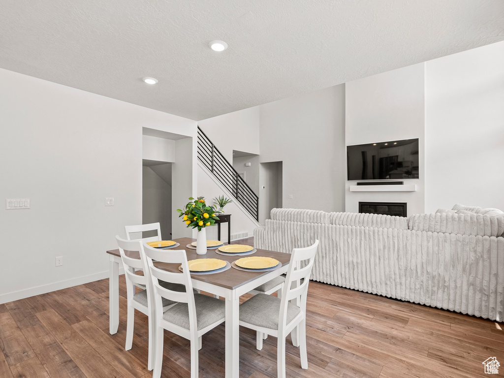 Dining space with light wood-style flooring, recessed lighting, a glass covered fireplace, and stairs