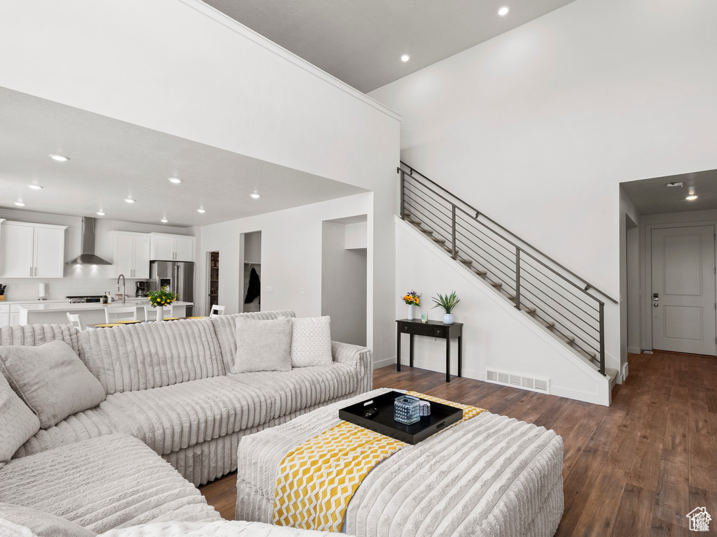 Living room featuring recessed lighting, stairway, dark wood-style floors, and a high ceiling