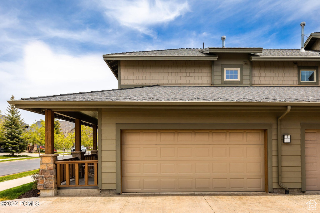 View of front of home featuring an attached garage, a shingled roof, and driveway