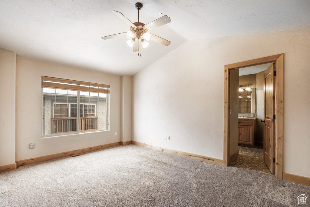 Spare room with carpet floors, vaulted ceiling, and a ceiling fan