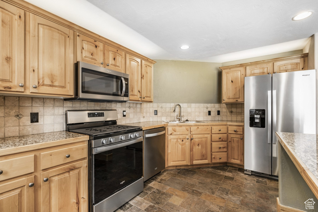 Kitchen featuring appliances with stainless steel finishes, tile countertops, light brown cabinetry, decorative backsplash, and recessed lighting