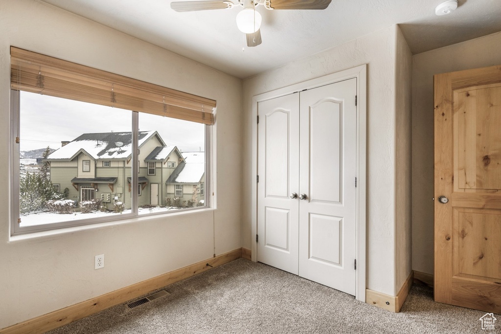 Unfurnished bedroom featuring multiple windows, carpet floors, a closet, and ceiling fan