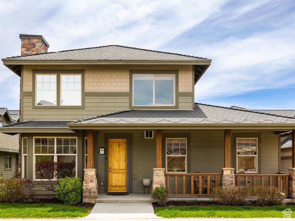Prairie-style house with a porch, a chimney, a shingled roof, and a front yard