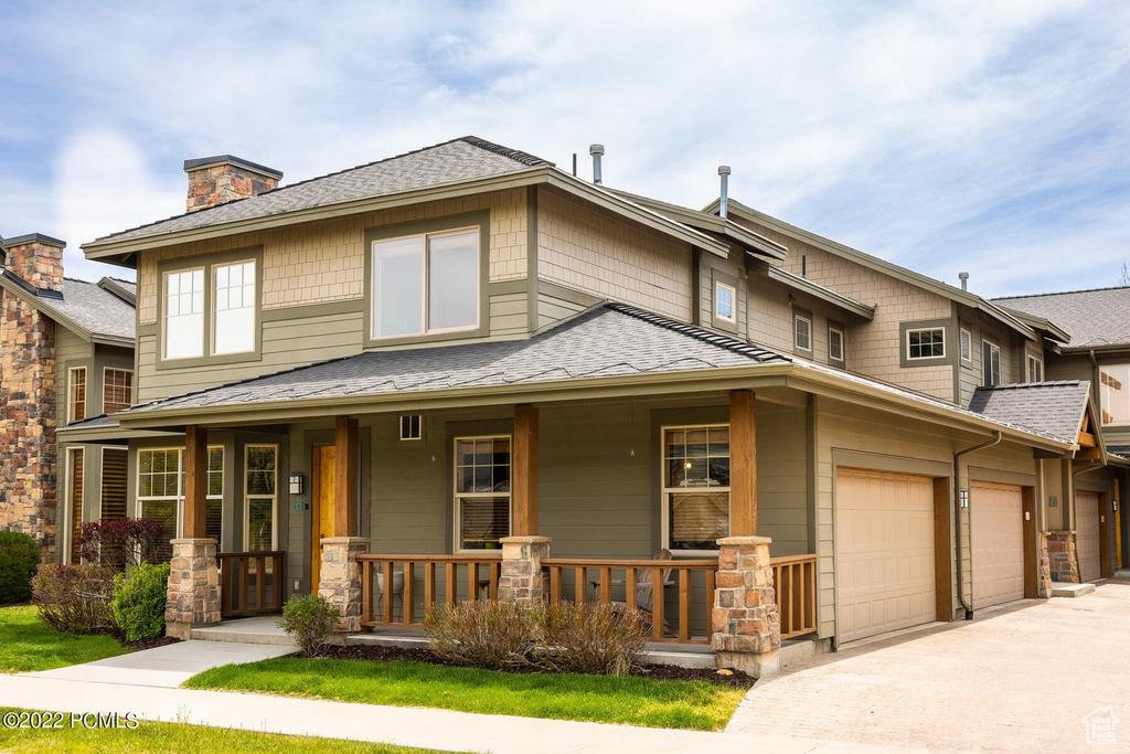 View of front of house with a porch, driveway, a shingled roof, and a chimney