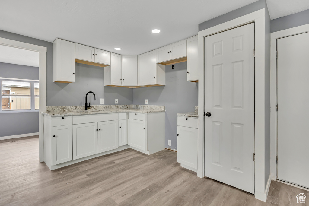 Kitchen with white cabinetry, light wood finished floors, light stone countertops, and recessed lighting