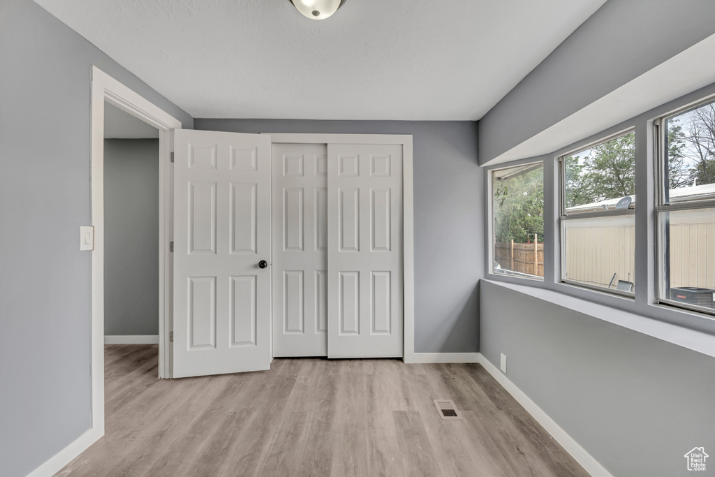 Unfurnished bedroom with light wood-type flooring and a closet