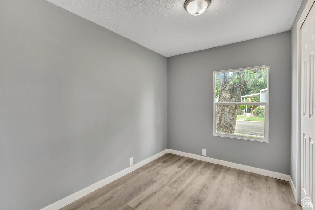 Empty room with wood finished floors and a textured ceiling
