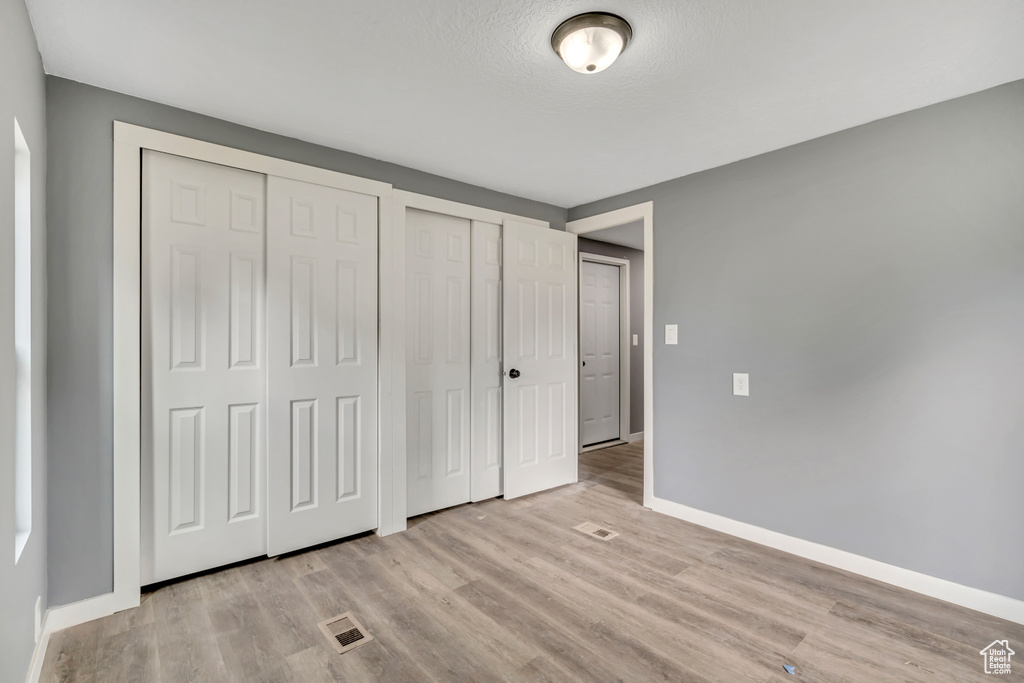 Unfurnished bedroom with wood finished floors and multiple closets