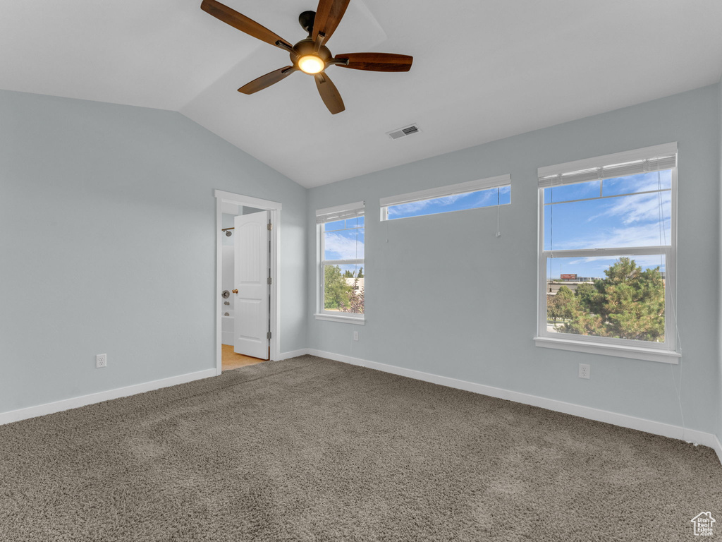 Carpeted empty room with ceiling fan and vaulted ceiling