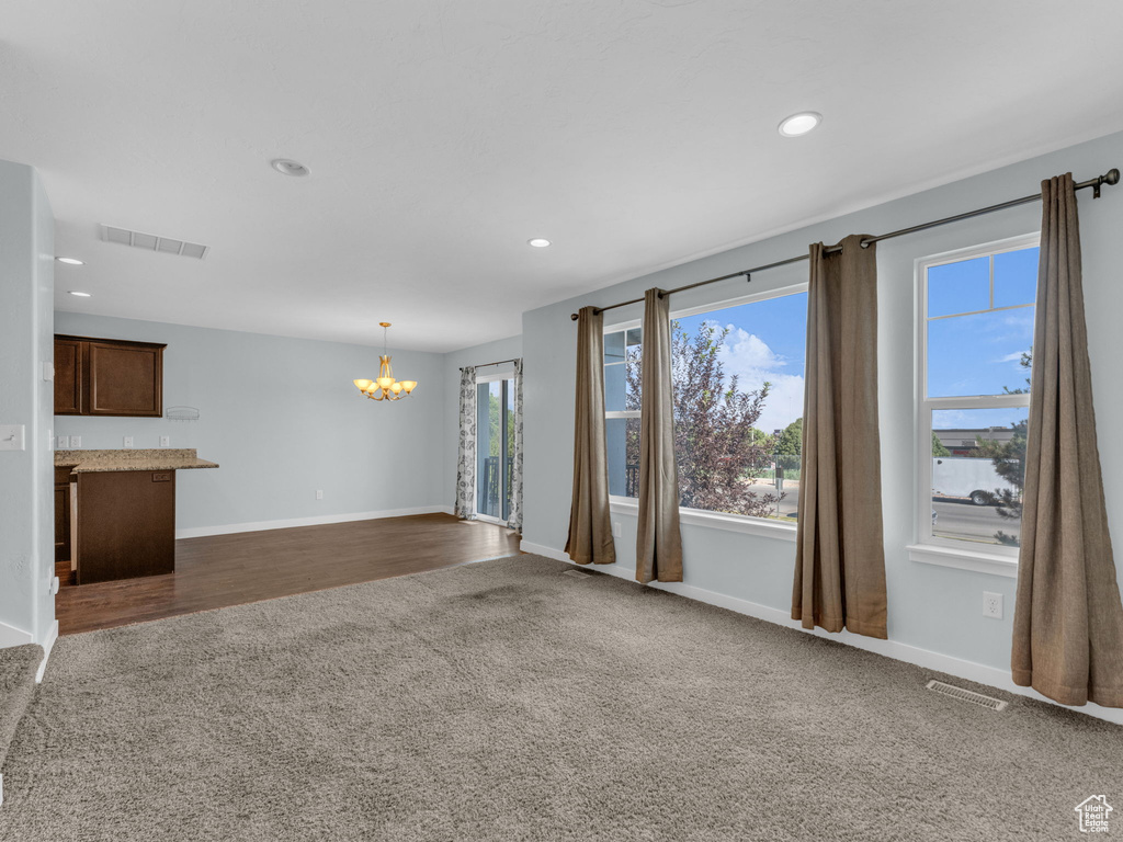 Unfurnished living room with dark carpet, a chandelier, and recessed lighting