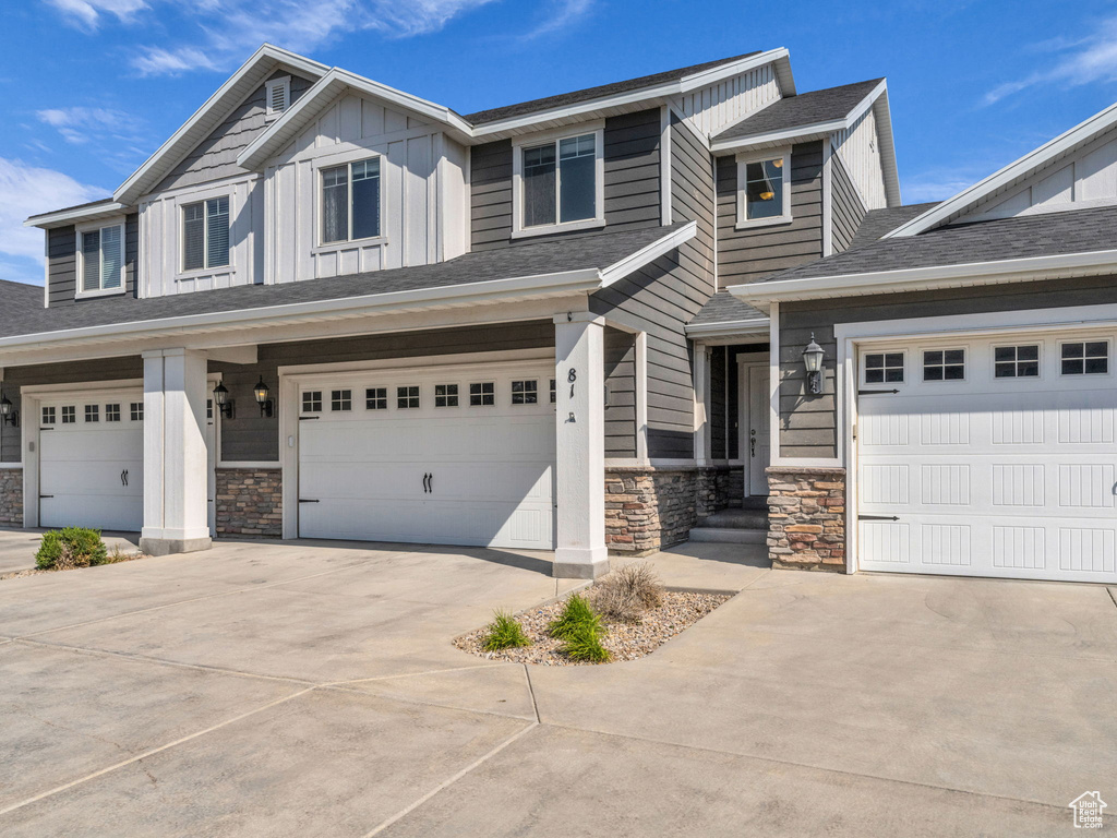Craftsman-style house with stone siding, driveway, and board and batten siding