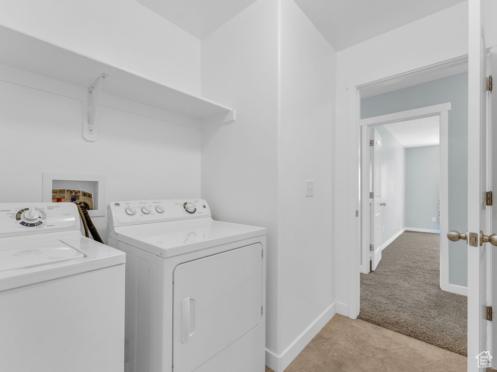 Laundry area featuring independent washer and dryer, light colored carpet, and light tile patterned floors