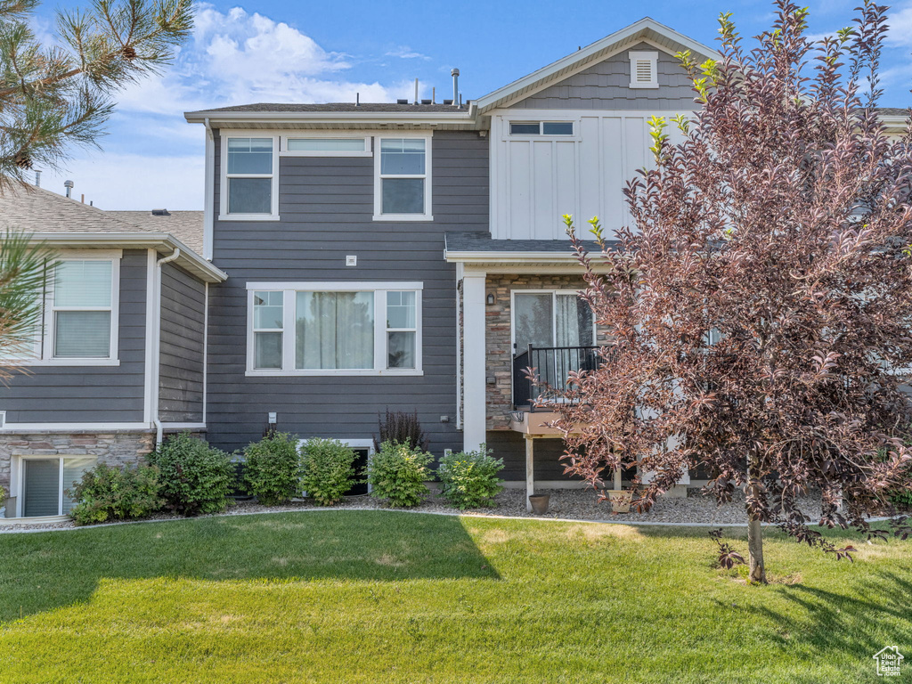 View of front of property featuring stone siding, board and batten siding, and a front lawn