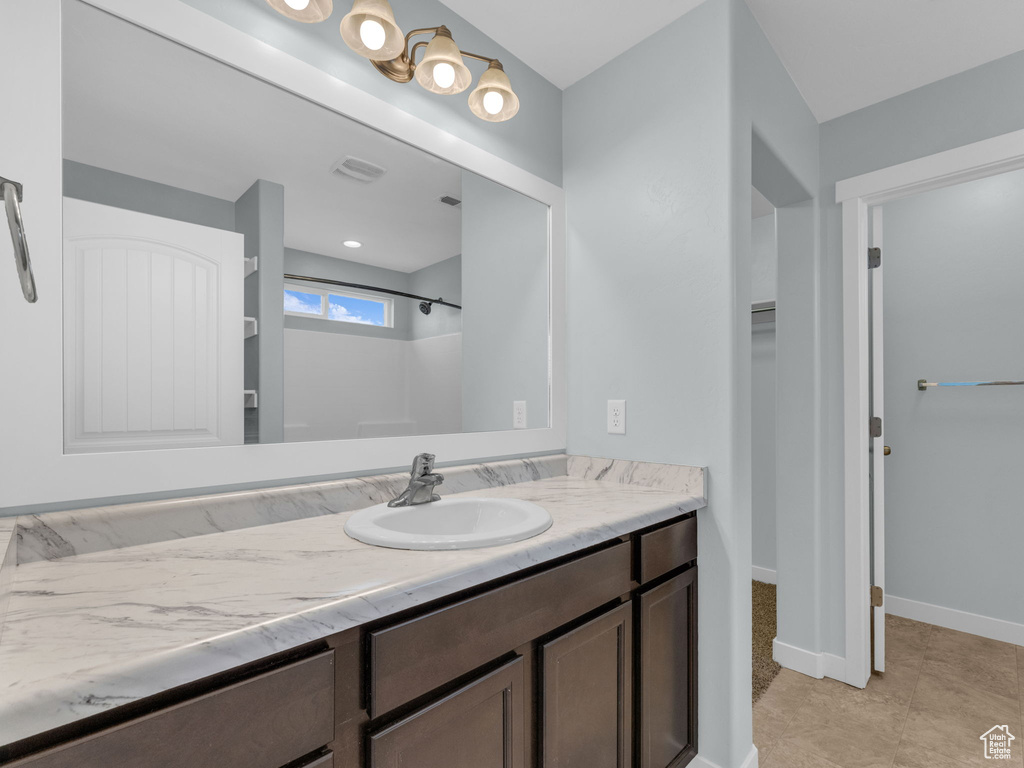 Bathroom with vanity, a shower, a spacious closet, and tile patterned flooring