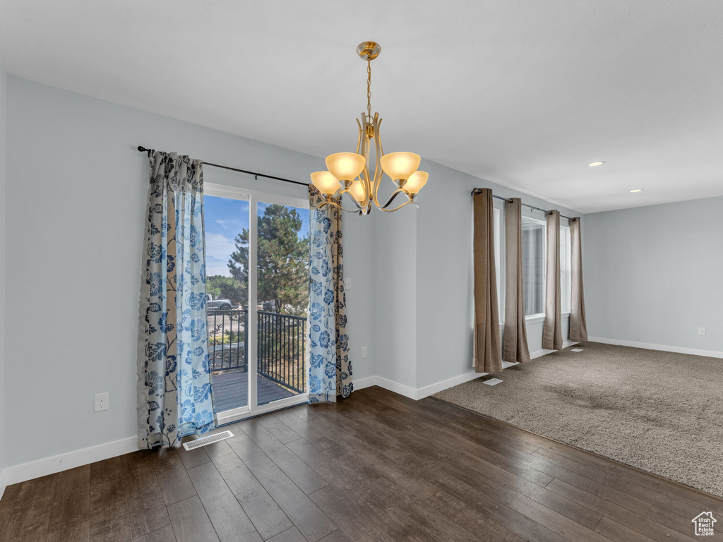 Empty room featuring a chandelier, wood-type flooring, and recessed lighting