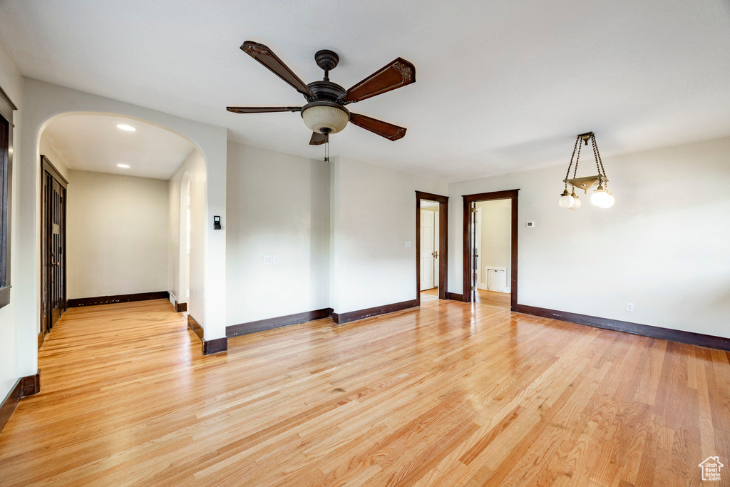 Unfurnished room with arched walkways, ceiling fan, and light wood-style flooring