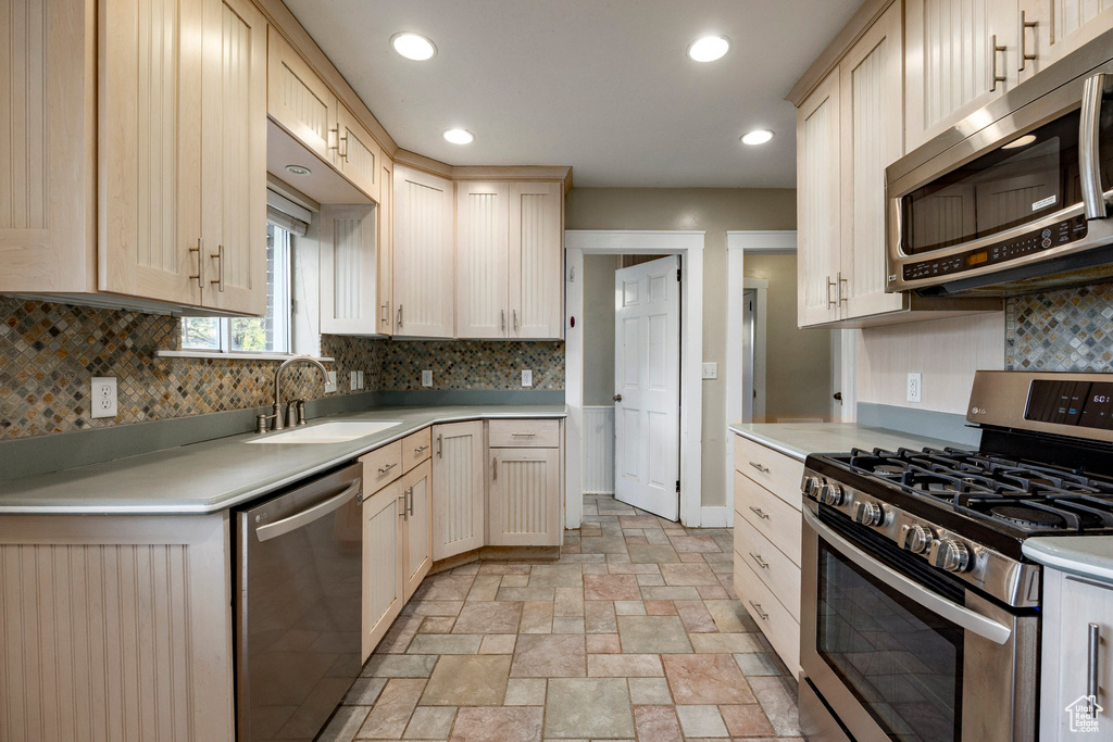 Kitchen with appliances with stainless steel finishes, light countertops, backsplash, recessed lighting, and light stone finish flooring