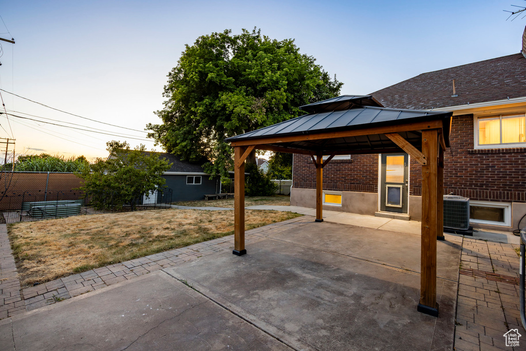 Patio terrace at dusk featuring a patio area and a gazebo