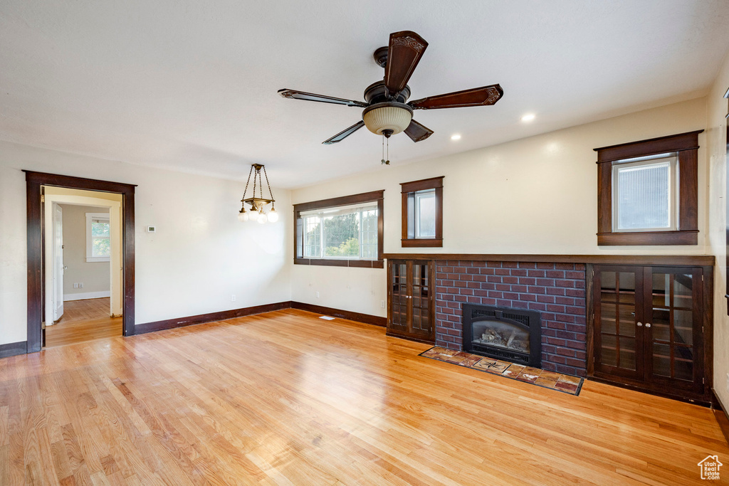 Unfurnished living room with healthy amount of natural light, a fireplace, light wood-style flooring, a ceiling fan, and recessed lighting