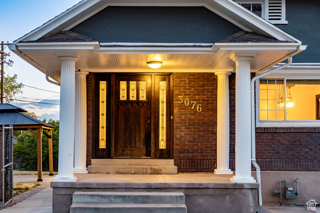 Entrance to property with covered porch and brick siding