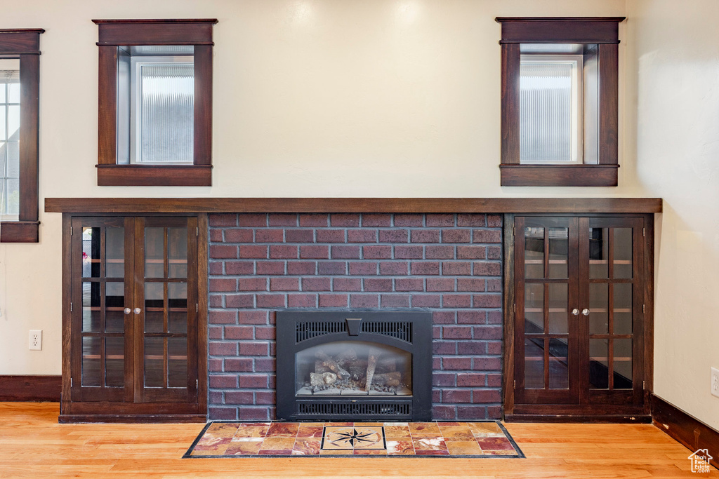Detailed view of wood finished floors, a brick fireplace, and french doors