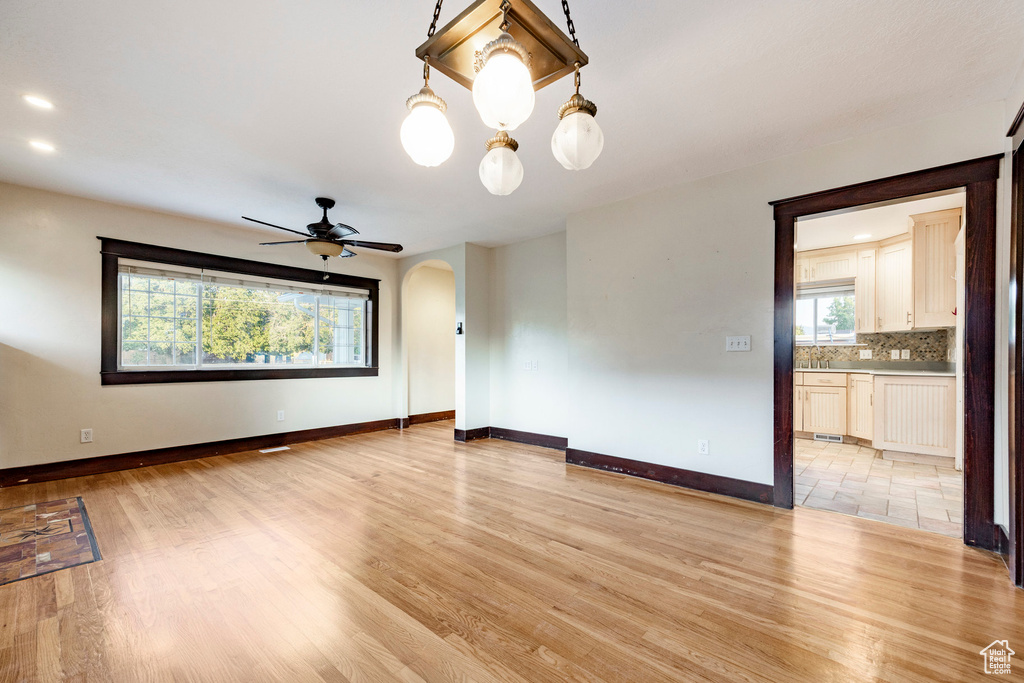 Unfurnished room featuring arched walkways, light wood finished floors, a ceiling fan, and recessed lighting
