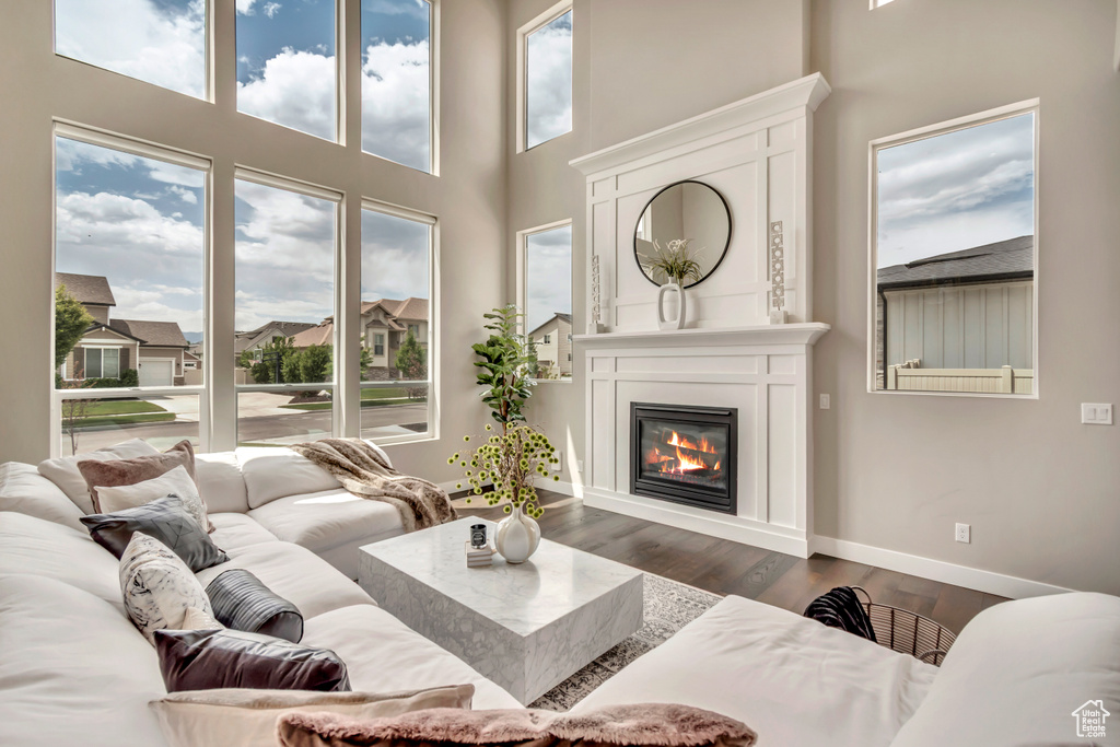 Living area with a glass covered fireplace, a towering ceiling, and dark wood-style flooring