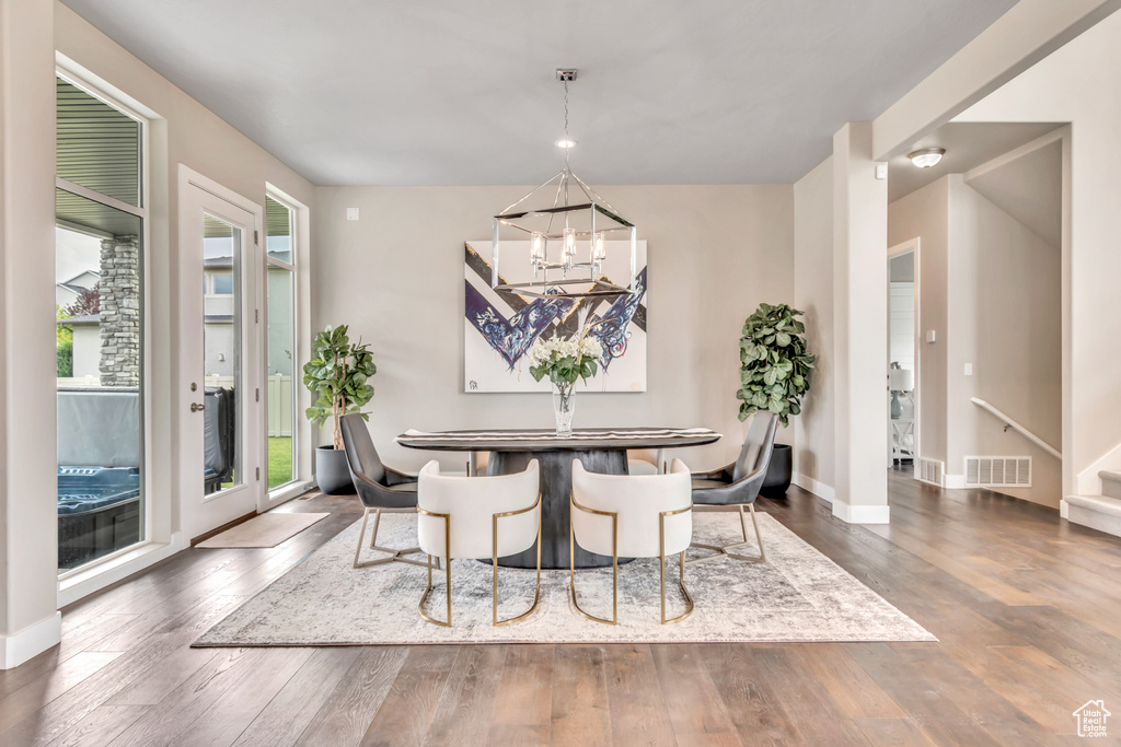 Dining room with a chandelier, healthy amount of natural light, hardwood / wood-style flooring, and stairway