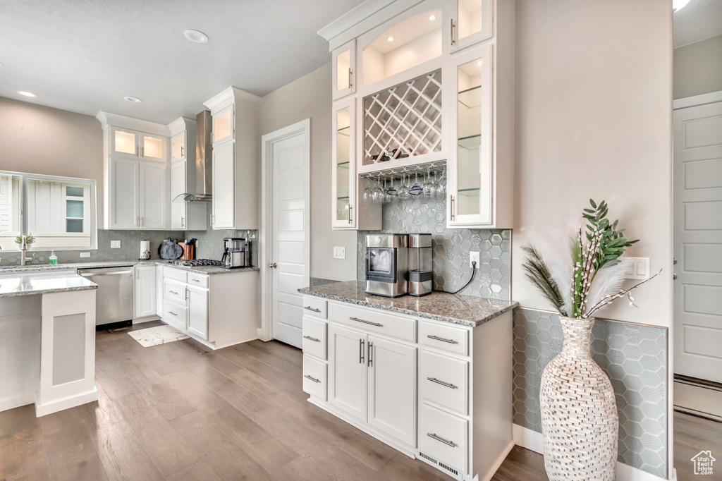 Kitchen featuring stainless steel appliances, wall chimney range hood, backsplash, white cabinets, and recessed lighting