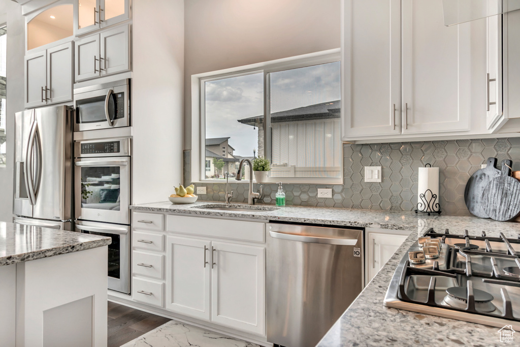 Kitchen featuring stainless steel appliances, white cabinetry, backsplash, and healthy amount of natural light