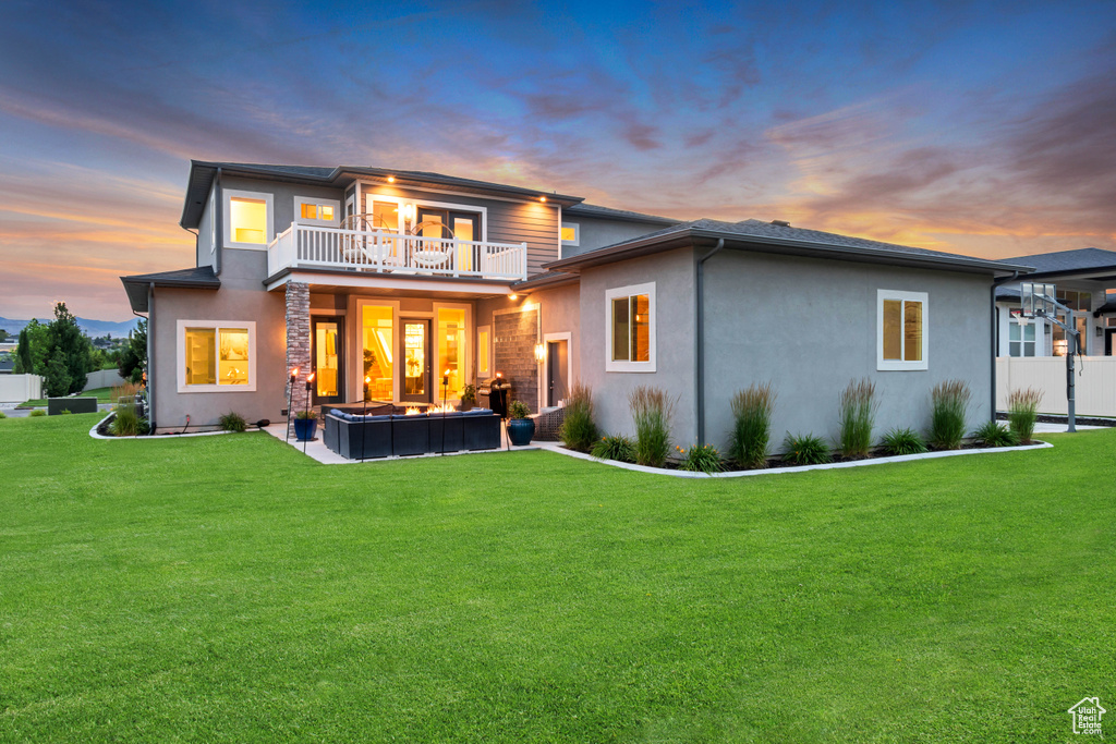 Rear view of house featuring a balcony, stucco siding, and a patio