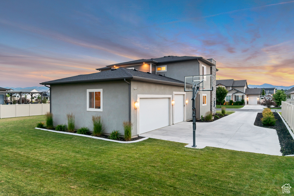 Property exterior at dusk featuring an attached garage, stucco siding, driveway, and a residential view