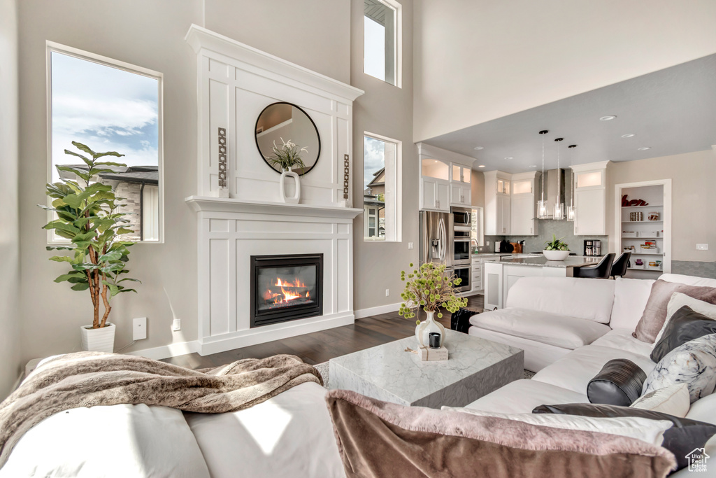 Living area with dark wood-type flooring, a large fireplace, and a high ceiling