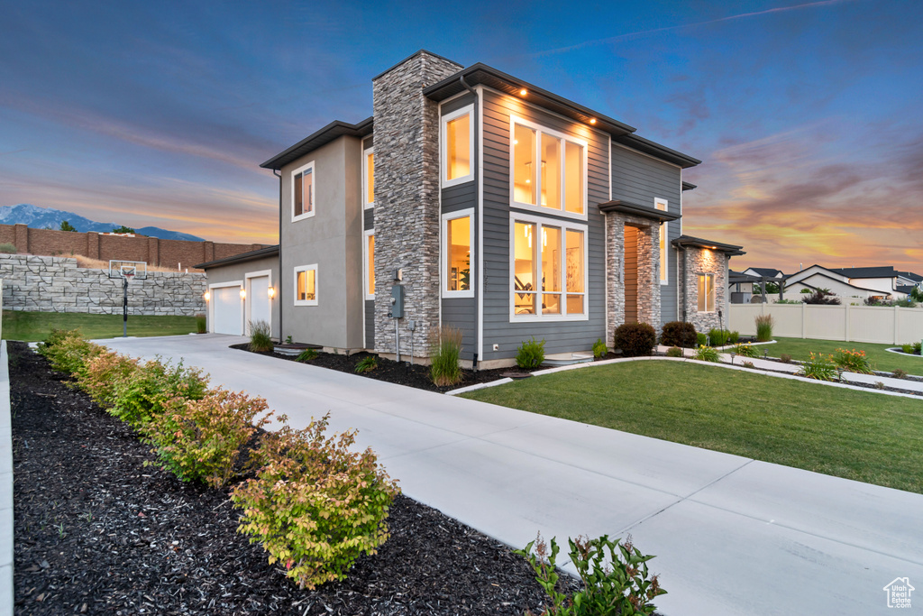 View of front of home with concrete driveway, an attached garage, stone siding, and a chimney