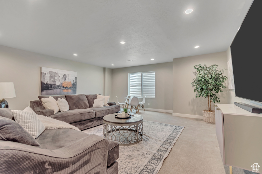 Living area with light carpet and recessed lighting